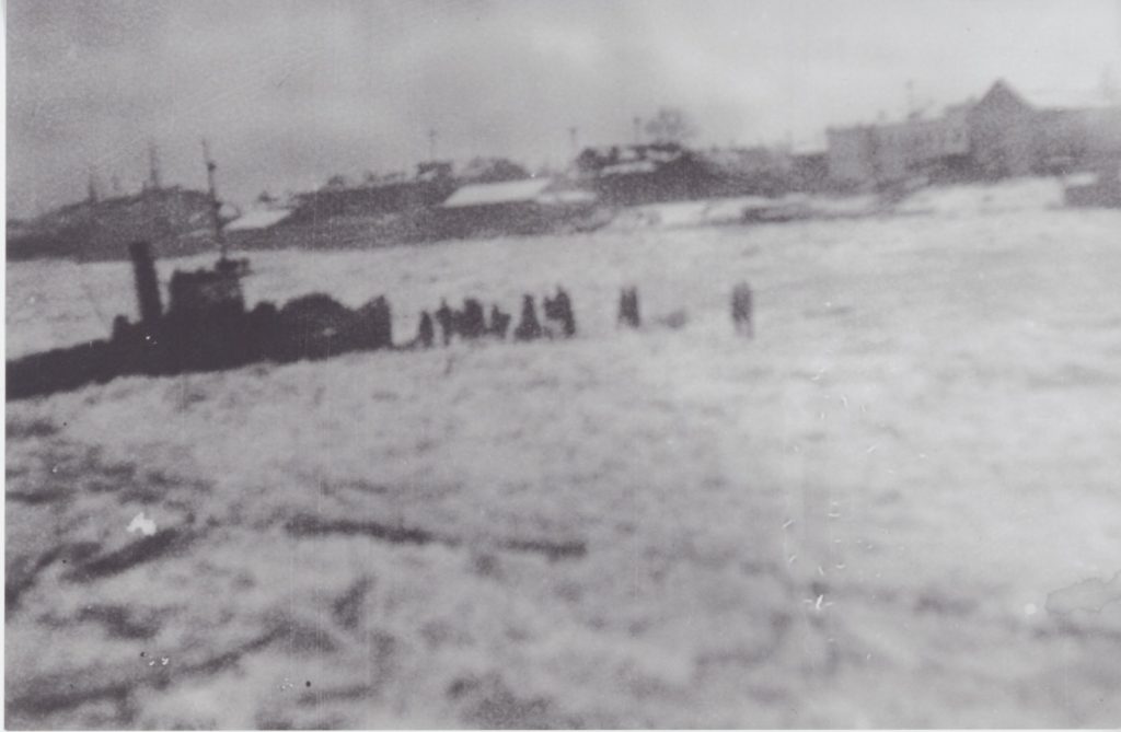 People walk over frozen water to unload ships in either Murmansk or Archangel